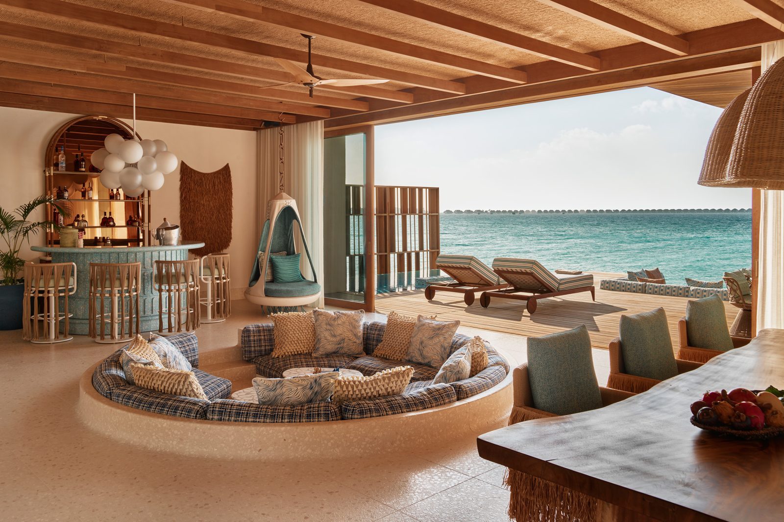 Offener Innenraum mit Bar, runder Sitzecke, Hängesessel, Ballon-Dekor, Deckenbalken und Meerblick.